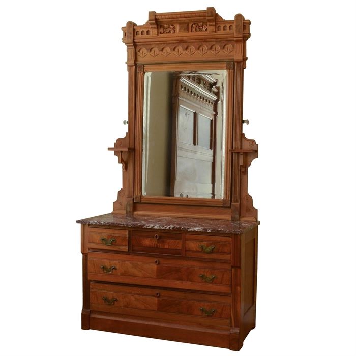 Antique Eastlake Dresser: An antique Eastlake dresser. Constructed of oak and oak veneers, this dresser has an incised and carved floral design, a tilting beveled mirror with glass knobs that is flanked on each side with a candle stand, a brown marble top, three small dovetailed drawers to the top with two larger dovetailed drawers below. The dresser sits on four porcelain casters. Matching pieces include a Eastlake bed 17CIN454-001 and wash stand 17CIN454-003.