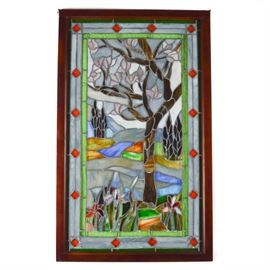 Stained Glass Window: A stained glass window. This window is made of individually cut pieces of slag and textured glass in a polychrome palette. It depicts a single tree with pink blossoms. Colorful iris are seen in the foreground. It is supported in a stained wooden frame and hangs by brackets attached to the top corners.