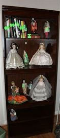 More collectible dolls with brides dolls in a bookcase.