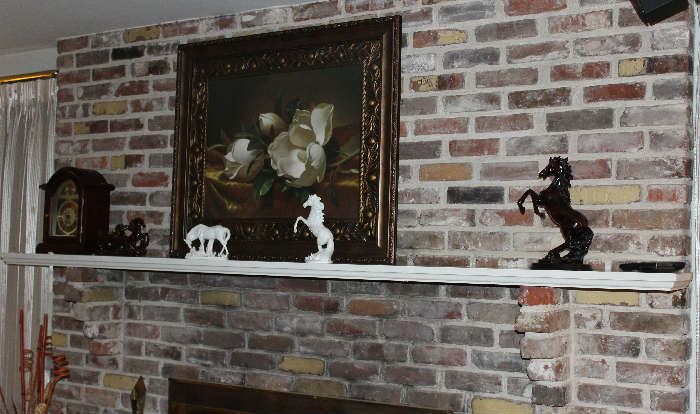 A close-up of the horses on the mantle with the beautiful picture.