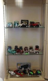 A collection of model cars in white curio cabinet.