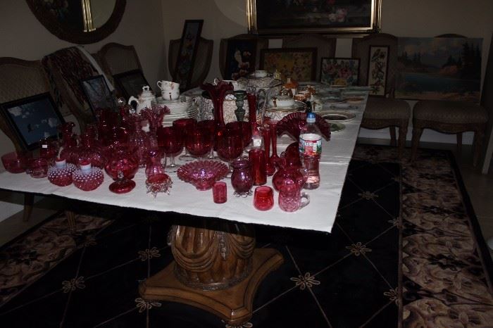 dining table full of cranberry glass and bone china, chairs adorned with framed needle point.