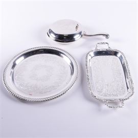Wm A. Rogers Silver Plated Silent Butler with Trays: A grouping of silver plated tableware. This includes a silent butler by Wm A. Rogers with hinged lid and a handle to one side. It is presented with a round tray with etched well and a rectangular tray with handles and intricate floral and acanthus leaf motif lip.