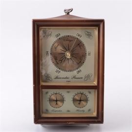Hall Weather Station: A hall weather station. This weather station includes a barometer set above a thermometer and hygrometer. The instruments are presented in a wooden frame with gold tone paint. The barometer is marked “Cooper” at the base of the gauge.