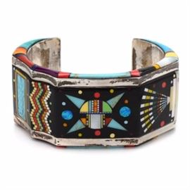 Sally Yazzie Navajo Signed Multi-Stone Sterling Silver Cuff Bracelet: A Navajo sterling silver and multi-stone cuff bracelet signed by Sally Yazzie. The wide cuff is faceted in shape with intricate inlay in mother-of-pearl, malachite, turquoise, enamel and synthetic stones to create various designs. The bracelet is unique with stone inlay at the side of the cuff as well.