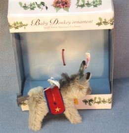 Steiff baby donkey Christmas ornament 717 in grey  mohair.  North American Exclusive.  This baby grey  donkey is wearing a red and blue felt blanket  with golden embroidery.  Has a braided cotton  tail.  Ltd. #0387 of 2003.
