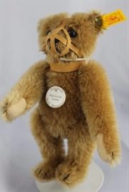Steiff Teddy Bear - Teddy With Muzzle Mini-102 Mohair-It brown/flannel-It. tan.  Jtd. light brown  mohair bear wearing a beige leather muzzle.  Has  light tan flannel paw pads and white historic  chest tag "Maulkorb Teddy".
