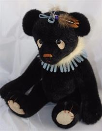 Sandy Schroeder- Schroeder Bear.  Little  Feather-214. Beige suede paw pads.  Blue suede  with fur ruffle around neck.  Blue suede, beads,  and feather head decoration.  Ltd. #06 of 50. Size:  12" H
