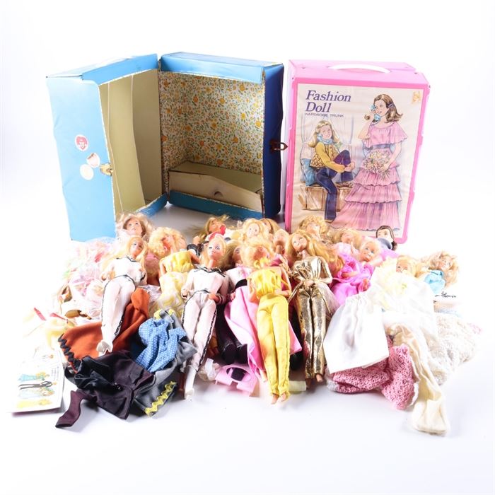 1970s and 1980s Barbie Assortment with Accessories: An assortment of 1970s and 1980s Barbies with accessories. This assortment features fourteen Barbie dolls and one Ken doll produced in the 1970s and 1980s by Mattel. The dolls wear a variety of Barbie and handmade clothing and include an assortment of loose clothing pieces with accessorizes such as shoes and purses. Also included are two storage trunks by Barbie and a vintage plastic doll.