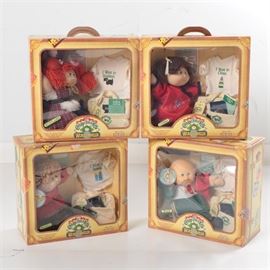 Four World Traveler Cabbage Patch Kids: A collection of four World Traveler Cabbage Patch Kids dolls. Each doll festures outfits, a t-shirt, faux birth certificates and passports from Russia, Spain, China, and Scotland. Each doll comes in their original handled box, printed to look like a suitcase with the Cabbage Patch Kids World Traveler logo to the front.