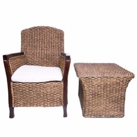Seagrass Woven Armchair and Ottoman: A seagrass woven armchair and ottoman pairing. the chair has a dark stained wooden arms with a removable white square cushion. The ottoman is slightly curved curved with a square top and base. There is a tag attached to the armchair that reads “Made in Indonesia.”