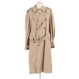 Men's Burberry Trench Coat: A men’s Burberry trench coat. This cotton blend coat is designed with slash pockets, epaulets, double-breasted button closure, and classic plaid lining. It is labeled to the interior “Burberrys, made in England, agents: A.B. Nordiska Kompaniet Stockholm.”