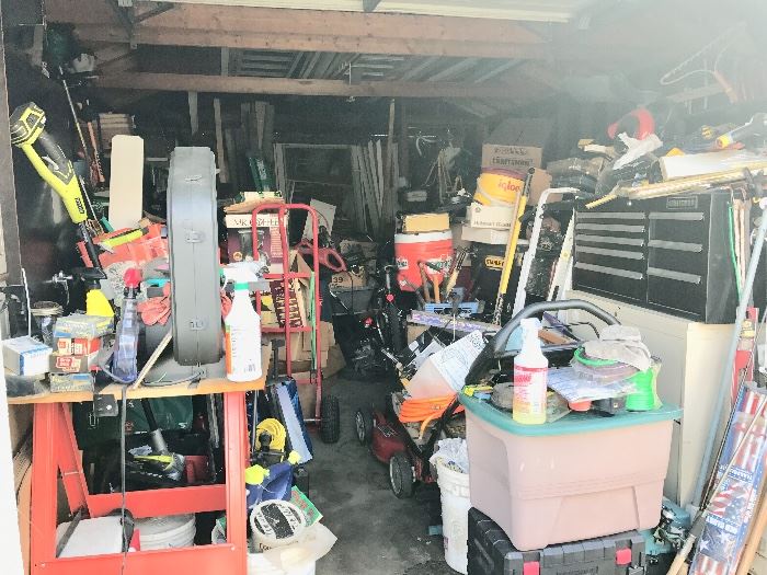 Garage full of tools, bikes, ladders, and lawn equipment.
