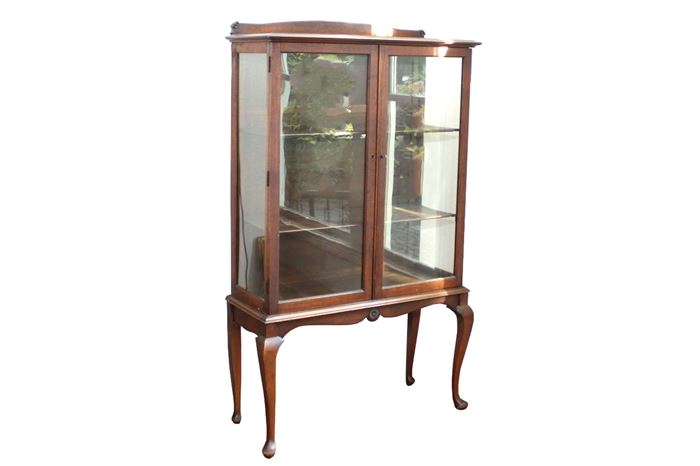 Antique Queen Anne Mahogany China Cabinet: A Queen Anne mahogany china cabinet having two glass front locking doors opening to three illuminated shelves with plate grooves. It is raised on 20” high Queen Anne legs with pad feet. This piece is located on the main level of the home.