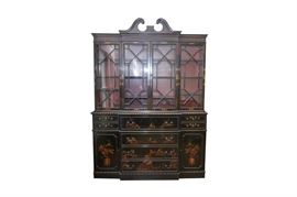 Vintage Hand-Painted Chinoiserie Breakfront Secretary by Union National: A vintage hand-painted chinoiserie breakfront secretary bookcase by Union National . The upper cabinet features a split pediment with dentil and fluted detailing over glass doors opening to four levels of display. The center section is lighted. The base cabinet features four center drawers flanked by two small drawers over single doors opening to reveal two levels of storage. The top center drawer features a drop front that opens to a pull out writing surface, small cabinet, four open cubicles, and four drawers. This cabinet features a hand-painted finish rendered in muted hues to a black lacquer base. The upper cabinet interior and drop-front desk are painted a deep red. This piece features open ring, teardrop, and bail pull hardware. A maker’s plaque is attached to a drawer interior. It is signed to the lower right door by the artist, Genoa. This item is located on the main level of the home. Professional movers