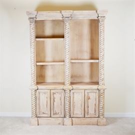 Greek Revival Style Distressed Wood Bookcase: A Greek Revival style distressed wood bookcase. In a light tone crackle finish, this bookcase features a twisted column and capital design, with upper open shelving and lower storage. This one piece unit includes three total adjustable shelves and shelving with storage behind the recessed panel doors.