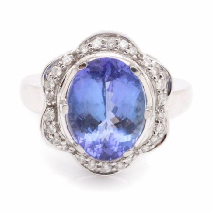 18K White Gold 5.38 CT Tanzanite and Diamond Ring: An 18K white gold 5.38 ct tanzanite and diamond ring. This item features prong set oval faceted tanzanite that is surrounded by a halo of diamonds in a scalloped pattern.