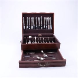 Oneida "Lasting Spring" Sterling Silver Flatware Set: A set of sterling silver flatware by Oneida. This in the Lasting Spring pattern, first introduced in 1949, which features a slightly flared handle on a slender stem with budding decoration to one side of the tip. This seventy-eight piece set includes eight dinner forks, twelve salad forks, ten teaspoons, five soup spoons, four iced tea spoons, an infant feeding spoon, a baby spoon and fork, a youth spoon and fork, two sugar spoons, a pickle fork, sugar tongs, a ladle, a meat fork, a serving spoon, and a pierced bon bon spoon. They are presented with twelve dinner knives, twelve butter spreaders, a master butter knife, and a youth knife, all with stainless blades and sterling handles. The set is presented in a Reed & Barton wooden flatware chest with brown felt-like interior lining.