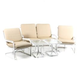 Patio Furniture Set: A patio furniture set. This set features a white metal frame settee and two side chairs with taupe upholstered cushions. Also included is one rectangular side table with a white metal frame and a frosted glass top. The cushions are by Bojer Inc.