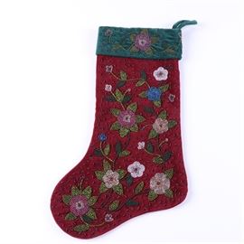 Beaded Stocking: A beaded stocking. This piece features a red boot with green cuff and loop. It has beaded floral patterns in a palette of pink, blue, and green. A tag reads “Made in India”.