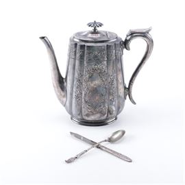 Walker & Hall Silver-Plated Coffee Pot with Spoon and Knife: A silver-plated coffee pot by Walker & Hall of Sheffield, England. This piece features an ovoid shape with scalloped sides, intricate foliate engraved decoration, a curved handle with holes at the two ends, and a hinged lid to the top, raised on an oval foot. It has a personalized engraving to one side and is marked to the underside “52 Patent Handle 3245” and “W&H Walker & Hall Silver Cutlers & Silversmiths Sheffield 552F 5 E”. The coffee pot is presented with an Amboise souvenir spoon with engraved bowl and a butter knife by J.E. Caldwell & Co. of Philadelphia.