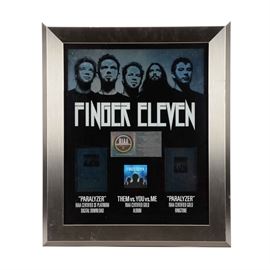 Finger Eleven's Q102 Award: An award presented to Q102 to thank them for Finger Eleven’s success in selling millions of compact discs. Presented in a beveled edge frame with a duo-tone image of the Canadian rock band Finger Eleven above bold white letters “FINGER ELEVEN” and their tracks “Paralyzer” and “Them vs. You vs. Me”. A thin metal plaque is centered on the display, reads, "Presented to WKRQ To Commemorate RIAA Certified Gold Sales of More Than 500,000 Copies of Finger Eleven’s Album ‘Them vs. You vs. Me’ Multi-Platinum Sales Of More Than 2,000,000 Digital Downloads of ‘Paralyzer’ And Gold Sales of More Than 500,000 Ringtones Of “Paralyzer’ Released On Wind-Up Records”.
