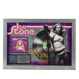 Joss Stone "Mind Body & Soul" Framed Award: A Joss Stone “Mind Body & Soul” Q102 award. The award is to commemorate the English singer, songwriter, and actress, Joscelyn Eve Stoker (1987 – ) for her second album “Mind Body & Soul” released in 2004. Presented in a beveled edge frame it features a die-cut figure of Joss, during a concert with a silver-tone album and disc in the backdrop. The background poster is a black design with a purple vignette border; “Joss Stone” is printed in pink and red with a black keyline. “Mind Body & Soul” is printed on the protective acrylic cover in yellow. The disc’s cover and a silver shaded metal plaque which is labeled, “Presented to WKRQ – CINCINNATI To Commemorate RIAA Certified Platinum Sales of More Than 1,000,000 Copies of the S-Curve/Virgin Records Compact Disc ’Mind Body & Soul”.