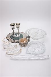 Collection of Silver Plate, Crystal, and Glass Tableware Including Godinger: A mixed collection of tableware. This selection includes twelve pieces. It features six silver plate pieces with a grape and vine motif including a cheese plate with a marble center with a matching cheese knife, two Godinger wine goblets, a coaster holder with a cork center, and a stopper. These pieces are accompanied by six pieces composed of crystal and glass, including a cake plate with a sawtooth rim, a cut laurel leaf band, and a hobstar to the center, two small oval dishes with frosted flowers designs to the center and gilt trim, a bowl in a cubist pattern accented with a with gilt trim, a leaf-shaped dish with a ribbed design, and an olive serving tray with a ribbed pattern.