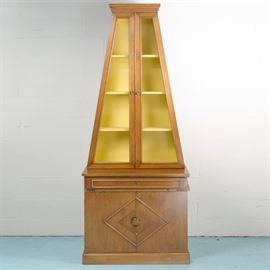 Mid Century Modern Display Cabinet by Ronnie Brahms: A Mid Century Modern display cabinet by Ronnie Brahms. This two unit piece features a rectangular top with molded trim over a triangular frame with two cabinet doors featuring chicken wire panels opening to a yellow painted three shelf storage space. The lower base features a full width drawer above two cabinet doors terminating on a plinth base. It is marked “Designs by Ronnie Brahms Manufactured by H. Sacks & Sons, Inc”.