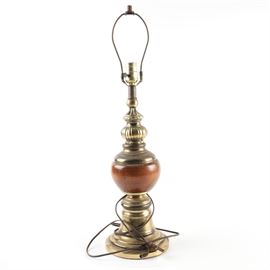 Brass Table Lamp: A brass table. The lamp has a harp and finial with one light socket and rotary switch dial. The lamp has a brass body with a brown center ball on a brass pedestal base. Powered on, but not otherwise tested.