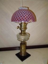 BAT:  Late 19th century American oil-burning lamp with cast iron base, embossed brass standard, pressed glass font, patented burner and rare cranberry-opal blown glass coin dot shade with ruffled rim.