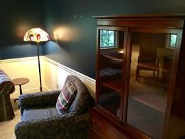 Overstuffed chair, bookcase, stained glass floor lamp