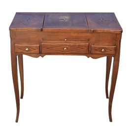French Provincial Style Inlaid Dressing Table: A French Provincial style dressing table in fruitwood, having an inlaid top with three, four-point stars, two placed in a lozenge border. The center lifts upward, having a mirror, while the flanking top panels fold outward, to reveal storage compartments. Below is a centered drawl-leaf, above three narrow drawers with lozenge border inlay. The table stands on slender cabriole legs. Circa 1920.