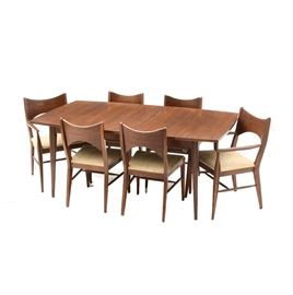 Mid Century Modern Dining Set: A vintage Mid Century Modern dining set, in walnut. It includes a table with an insert leaf and tapering legs, plus six chairs with beige fabric upholstered seats and spreader bases. Two of the chairs have armrests while the others are side chairs. Unmarked.