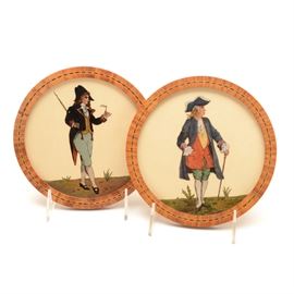 Pair of Reverse Paintings of Colonial Men on Glass: A pair of reverse paintings on glass depicting men in Colonial attire standing on a foreground with sparse flora. The images feature fine black outlining and crosshatching with color filled in behind. The backgrounds consist of ivory fabric with no added details. Each of these unsigned works is presented in a circular wooden frame with veneer inlay and a wire for hanging to the verso.