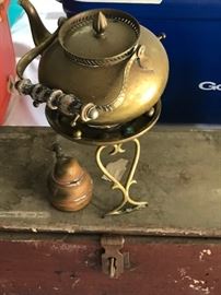 Vintage brass teapot on stand with burner; sitting on an antique painted wooden tool chest.