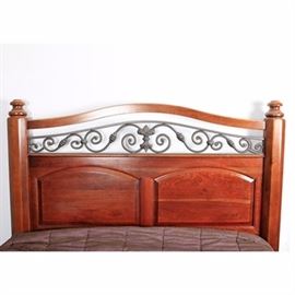 Cherry and Wrought Iron Queen-Size Bed Frame with Footboard: A paneled cherry bed frame with wrought iron detail, in queen-size. The headboard has a serpentine rail, above a wrought iron panel with scrolled design and fleur-de-lis, between octagonal posts. The lower footboard is matching, on bun feet. Includes side rails.