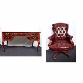 Chippendale Style Writing Desk with Leather Executive Chair: A Chippendale style writing desk with leather executive chair. This set includes a rectangular top desk with beveled edge over a knee hole drawer flanked by two stacked drawers. The drawers feature brass round plates with swan neck handles. The desk rises on cabriole legs and terminates on pad feet. Also includes an executive chair with curved crest rail and shallow wing sides with button tufted high back and seat cushions flanked by rolled arms with nailhead trim supports. The chair rises on a post and terminates on splayed legs with casters. There are no visible maker’s marks.