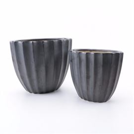 Pair of Ceramic Planters: A pair of ceramic planters. The pair features a large form and a small from with matching finishes and texture. The planters feature an scalloped oval opening leading to a ribbed texture along the body of the piece. Both planters are finished in a black matte glaze to the exterior and a peach glaze to the interior.