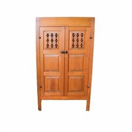 Pine Cabinet with Hand Cut Maltese Crosses: A pine cabinet with pierced Maltese Crosses. A basic pine cabinet with two hinged doors embellished with rows of cut Maltese Crosses. The doors also have raised panels and a primitive styled dark metal latch. The doors open to two shelves. The side panels are also cut with Maltese Crosses and the piece rises on four straight legs.