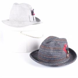Men's Fedoras Including Conway: A selection of two men’s fedoras. This grouping includes a grey twill fedora with a matching band and a black and red feather accent. It is marked to the interior “Marshall Field & Company the store for men, Conway.” Also included, a multicolored knit fedora with a matching band and a red and black feather accent. More, this assortment includes a white Martha Weathered hat box.