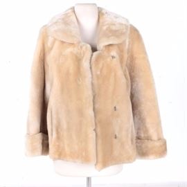 Women's Sheared Beaver Jacket: A women’s sheared beaver jacket. The blonde fur jacket features a cape collar, prong and loop closures, seam pockets, and cuffed sleeves. The interior lining includes a furrier label and embroidered monogram appliques.