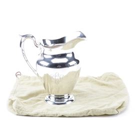 1957 Gorham "Puritan" Sterling Silver Water Pitcher: A sterling silver water pitcher from 1957 by Gorham. This is in the Puritan pattern, featuring a vase shaped body with personalized engraving “DGD” to the side, a curved handle, and a round base. It holds four-and-one-fourth pints of water and is stamped to the underside “Gorham” above the pseudo hallmarks of a lion, an anchor, and a Gothic ‘G’, “sterling 182”, the date mark for 1957, and “4 1/4 Pint”. The approximate weight is 20.135 ozt.