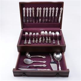 Westmorland "George & Martha" Sterling Silver Flatware Set for Twelve: A set of sterling silver flatware for twelve by Westmorland Sterling Co. This company was created by Wearever Aluminum and Wallace Silversmiths to sell sterling flatware and holloware directly to customers through door-to-door subscriptions, and all products were manufactured by Wallace Silversmiths. This collection is in the George & Martha pattern, which is the same as the Henry L. Wallace designed Hampton by Wallace, featuring curved handles with scrolled accents. The ninety-seven piece set includes twelve dinner forks, twelve salad forks, twenty-four teaspoons, twelve round soup spoons, twelve butter spreaders, two oval soup spoons, three serving spoons, a casserole spoon, two cocktail forks, a tomato server, and a ladle, all marked “Westmorland Sterling”. They also come with twelve dinner knives, a cake server, and a carving knife and fork set with stainless steel components and sterling handles. The set is pre