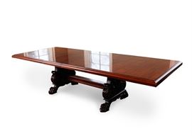 Vintage Mahogany Dining Table by Henredon: A vintage mahogany dining table by Henredon. This rectangular top table with beveled edges and two leaf inserts rises on two decorative supports. The supports feature curved edges with acanthus leaf carved panels joined by a stretcher and terminating on large claw and ball feet. The underside is marked “Henredon”.