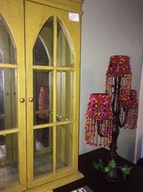 Yellow display cabinet; hot pink, red, and yellow beaded shades on candle holder
