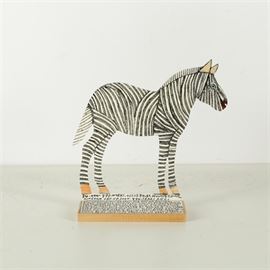 Reverend Howard Finster Zebra Shaped Painting: A painted zebra figurine by visionary folk artist, poet, and musician Reverend Howard Finster (American, 1916-2001), best known for his unique, outsider artwork that is often covered in Bible verses and other words. The piece depicts a black and white zebra mounted to a wood base. The zebra is hand-painted with stripes to the front and biblical lyrics to the verso. Additional lyrics are written on paper and applied to the wood base.