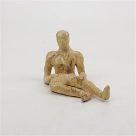 C. Wallen Signed Ceramic Figure: A ceramic figure, signed “C. Wallen.” The figure depicts a man reclining on the ground, with his legs stretched out in front of him and his torso propped up by his right elbow. It features a pale yellow glaze and is signed in black permanent marker to its underside.