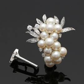14K White Gold Pearl and Diamond Foliate Brooch and Pearl Shortener: A 14K white gold cultured pearl and diamond brooch. This brooch features a stepped cluster of cultured pearls with 0.67 ctw diamonds ornamenting foliate accents. Included with this brooch is a detachable piece that allows the brooch to function as a a pearl shortener.
