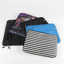 Assortment of Laptop Cases: An asssortment of laptop cases. The assortment includes a horizontal black and white striped case by Kate Spade; two Incase covers, in sky blue and black and a Cynthia Rowley case with a floral motif on a black background. All cases fit a laptop with a 16" screen.